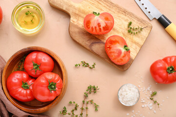 Bowl and board with fresh tomatoes on beige background