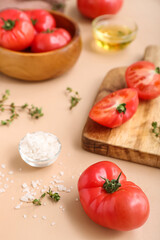 Bowl and board with fresh tomatoes on beige background