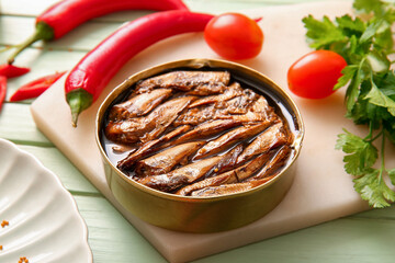 Board of canned smoked sprats with parsley and chilli on green wooden background