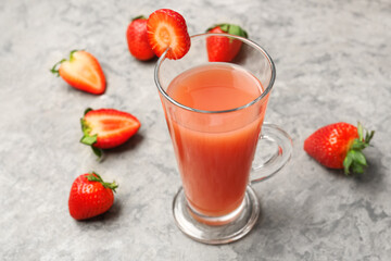 Glass with tasty strawberry smoothie on grey table