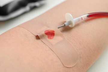Woman donating blood on beige background, closeup. World Donor Day