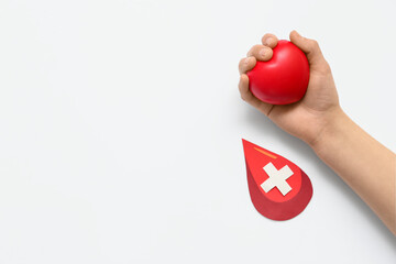 Woman holding grip ball and paper blood drop with cross on white background. World Donor Day