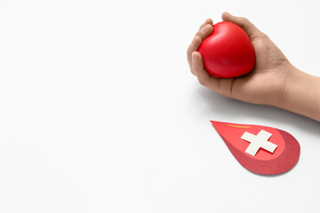 Woman holding grip ball and paper blood drop with cross on white background, closeup. World Donor...