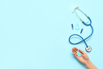 Woman with paper drops, test tubes and stethoscope on blue background. World Blood Donor Day