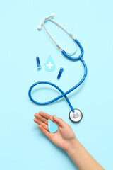 Woman with paper drops, test tubes and stethoscope on blue background. World Blood Donor Day