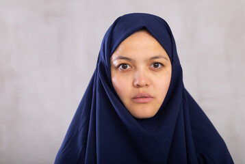 Portrait of young calm woman in hijab posing against background of studio - obrazy, fototapety, plakaty