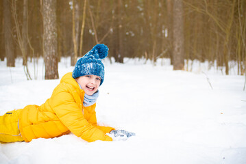Fototapeta na wymiar happy boy in yellow winter clothes lies on the snow