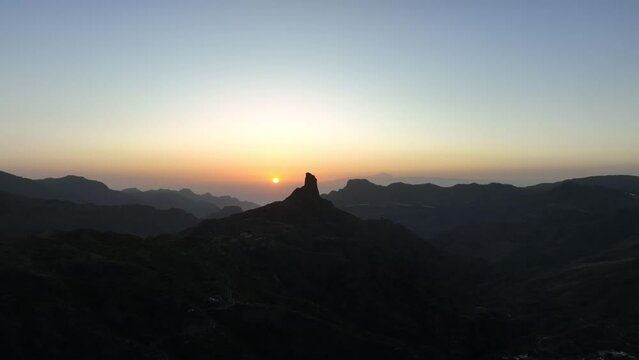 Aerial video of sunset behind Roque Bentayga on Gran Canaria with orange sky and silhouettes of Tenerife and La Gomera