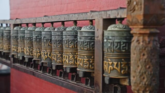 Woman spinning Buddhist prayer drums or prayer wheels in slow motion, Kathmandu, Nepal