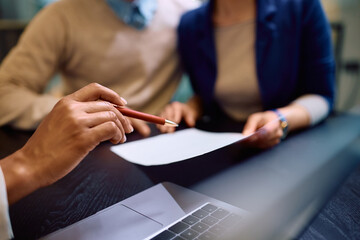 Close up of black financial advisor pointing at place of signature on contract during meeting with her clients.