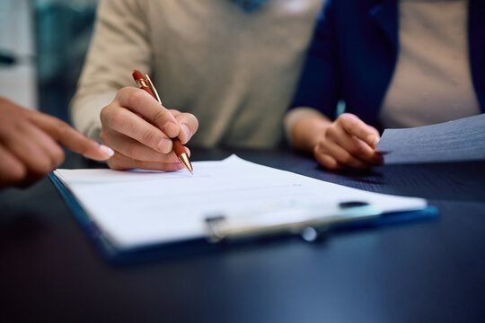 Close up of couple signing contract with bank manager in office.