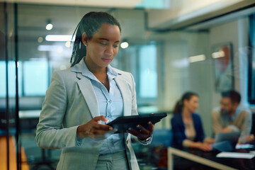 Black female financial advisor works on digital tablet in office.