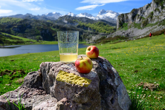 Glass of natural Asturian cider made from&nbsp;fermented apples with view on Covadonga lake and tops of Picos de Europa mountains, Spain