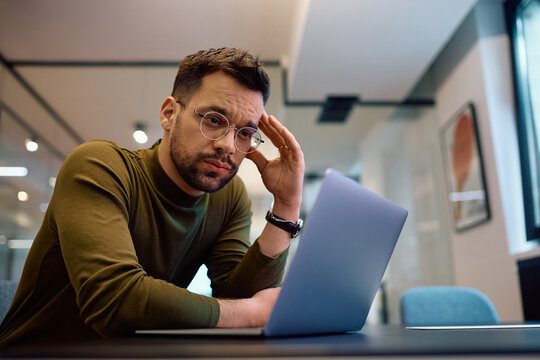 Worried businessman reading problematic email on laptop in office.