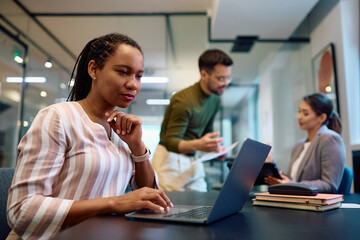 Fototapeta na wymiar Black female entrepreneur working on laptop in office.