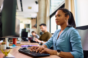 Fototapeta na wymiar Black female entrepreneur working on desktop PC in office.