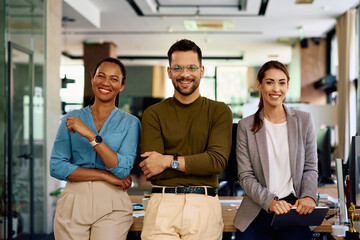 Happy business team in modern office looking at camera.