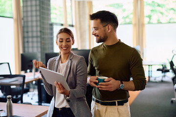 Young happy coworkers using digital tablet while working in office.