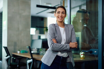 Young confident businesswoman in office looking away.