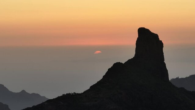 Aerial video of sunset behind Roque Bentayga on Gran Canaria with orange sky and silhouettes of Tenerife and La Gomera