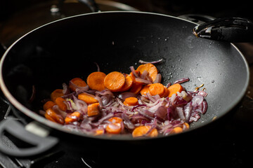 Onions and carrots are fried in a deep frying pan. Preparation for cooking.