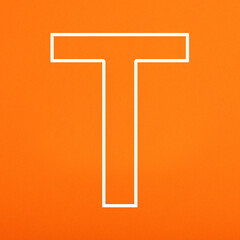 Letter T uppercase written in white color isolated on orange foamy background