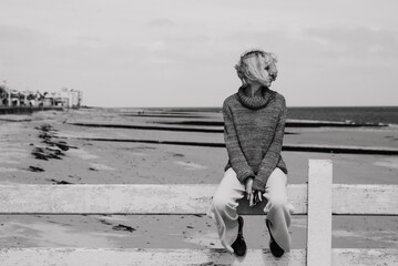 Thoughtful woman sits on the ocean. Middle age woman. Crisis, depression concept. Black and white photo.
