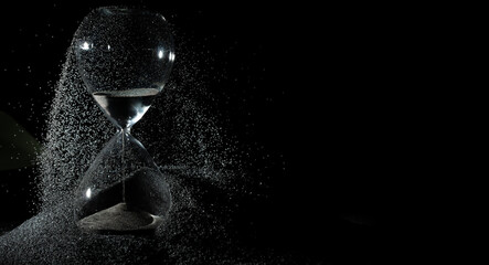 Hourglass add more sand of time on black sand over black background. Black hourglass show more time...