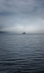 Naklejka premium A boat on the water with hazy clouds
