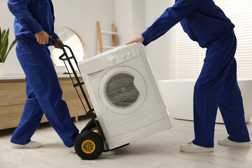 Male movers carrying washing machine in bathroom, closeup. New house