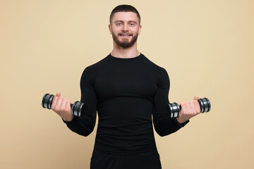 Fototapeta na wymiar Handsome sportsman exercising with dumbbells on brown background