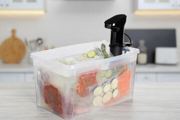 Sous vide cooker and vacuum packed food products in box on wooden table in kitchen. Thermal...