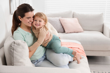 Obraz premium Mother with her cute little daughter on sofa at home, space for text
