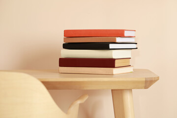 Stack of different hardcover books on wooden table indoors