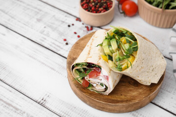 Delicious sandwich wraps with fresh vegetables and peppercorns on white wooden table, space for text