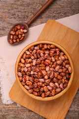 Bowl and spoon with dry kidney beans on old wooden table, flat lay