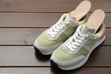 Orthopedic insoles in shoes on floor, closeup. Space for text