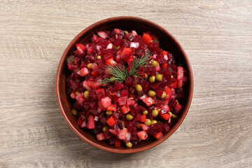 Bowl of delicious fresh vinaigrette salad on wooden table, top view