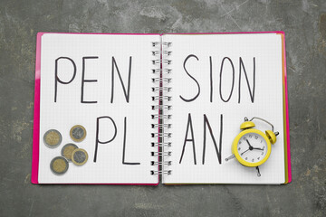 Notebook with words Pension Plan, coins and yellow small alarm clock on grey table, top view
