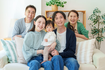 リビングで記念写真を撮る三世代家族