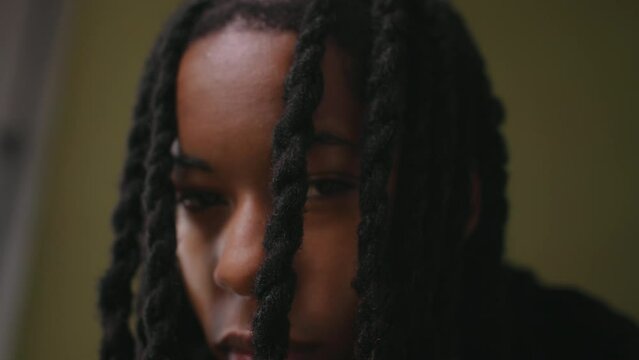 Close up of non binary person with braids looking at camera