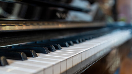 Piano keyboard in inclination angle with selective focus. Warm color toned image with orange light effect.Blur background with space.Black and white grand piano.Nobody or people.