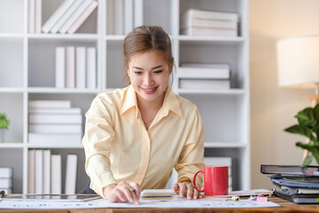 Portrait of female employee preparing report, doing paperwork at her office desk.