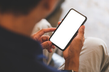 Over shoulder close up view, man holding smartphone with mockup white blank display, empty screen for advertise or text message.