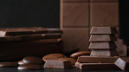 Stack of milk chocolate and dark chocolate bars on black background. Dessert food background.