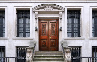 Apartment building or townhouse entrance with ornate stone design and elegant carved wooden front door - 603545512