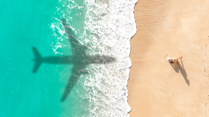 Airplane shadow flying over beautiful exotic tropical beach with woman sunbathing on a sunny day -...