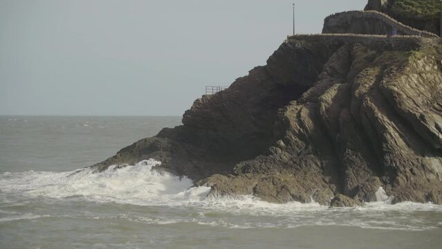 Roiled sea waves crashing on rocky cliff in North Devon