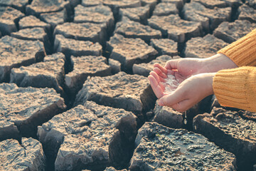 Water droplets in hand on barren ground.