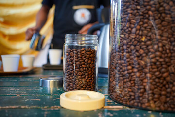 Brewing coffee on the table with coffee bean inside jar as foreground